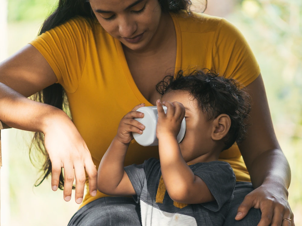 Mother with young boy on her lap, drinking from a cup