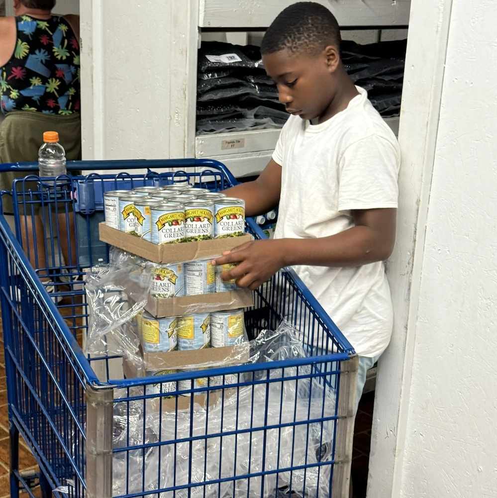Young volunteer unpacking food cans to stock in food pantry inventory